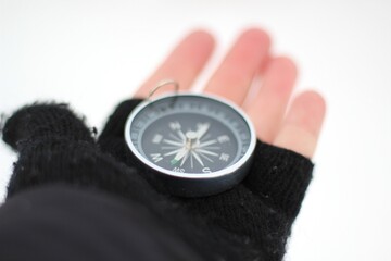 A compass in the human hand mitten in winter concept of navigation searching way season photo snowy