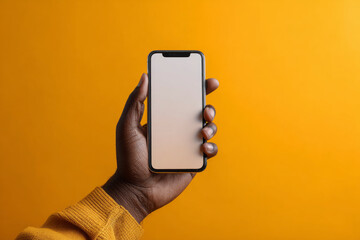 A hand holding a smartphone against a yellow background.