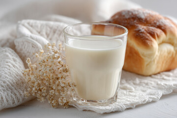 A glass of milk beside a soft bread roll.