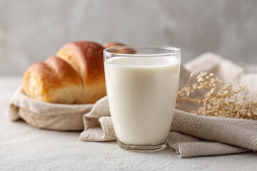 A glass of milk beside fresh bread rolls.