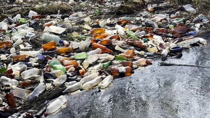 Dirty river is polluted with many plastic bottles. A lot of trash is dumped in open and freely available places at nature. Global environmental pollution problem. Concept of ecological disaster
