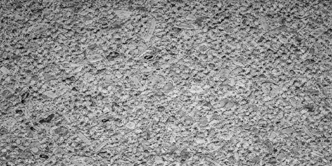 A rough black and white asphalt texture creates a grunge stone pattern on a weathered gray road surface for a macro material design background