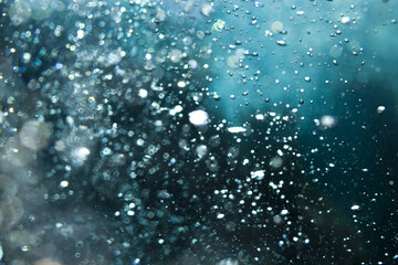 Abstract underwater view of sunlight shining through deep blue water with bubbles.