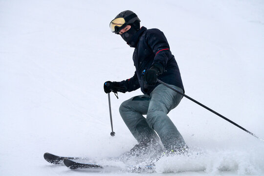 A skier speeds down a snowy slope. Snow dust flies out from under his skis.