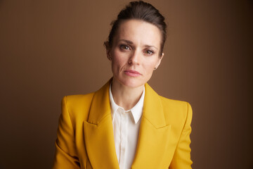 A professional woman in a striking yellow blazer looks directly at the camera with a serious, determined expression, embodying focus and strong business acumen.
