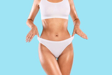 Close up shot of unrecognizable fit woman wearing lingerie pulling up white panties standing...