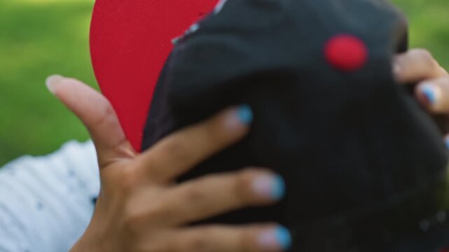 Youth capturing outdoors, Customizing cap carefully before training in park setting, Teenager adjusts headgear outdoors with detailed focus before engaging in park training activities