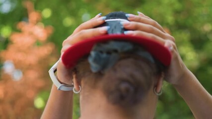 Active outdoor lady, Energetic woman prepares outside, Athletic young lady gears up in park surroundings, Vibrant female sports enthusiast adjusting her cap amidst natural outdoor scenery