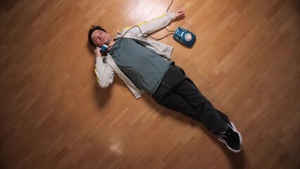 Man lying exhausted on a wooden floor, holding a retro rotary telephone to his ear, connecting with someone during a moment of rest or crisis, conveying feelings of despair or relaxation - Powered by Adobe