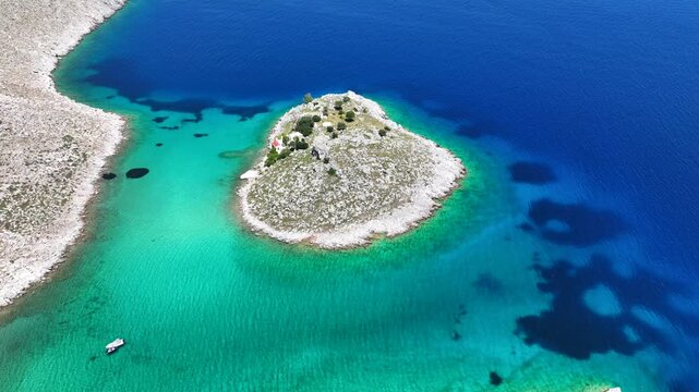 Aerial drone cinematic video of tropical exotic paradise bay with deep turquoise sea forming a blue lagoon visited by luxury yachts and sail boats