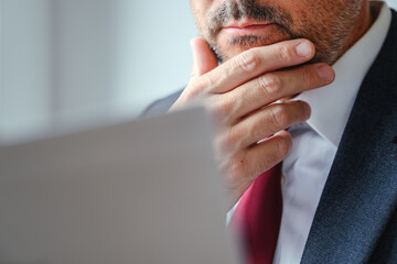 Pensive CEO manager analyzing report document with hand on chin, thinking and planning, reflecting on corporate strategy in office.