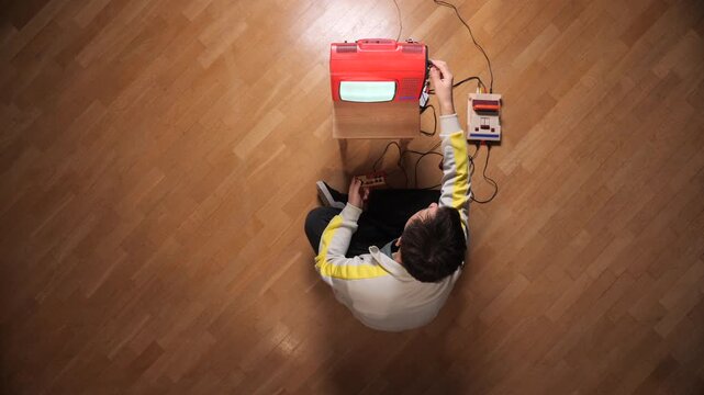 Person playing vintage video game with a classic console and smashing the old portable television screen out of frustration, attempting to fix connectivity issues