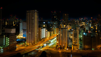 Obraz premium Tokyo night skyline with illuminated modern buildings and glowing streets, an aerial metropolitan view shimmering across Japan.