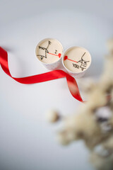 Valentine's Day cups with drawings and ribbon on a white surface during the celebration of love and friendship