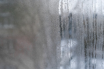 window with condensation, dreamy, textured background with water droplets and streaks ideal for creative applications. abstract background with visible condensation streaks and water buildup on glass.