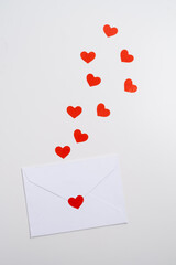 White envelope with red heart sticker and floating hearts. Romantic concept.