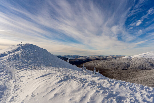 Frozen winter morning on Halicz peak in the Bieszczady Mountains. Snow-covered ridges, icy summit cross and clear sky along the popular Tarnica Halicz Rozsypaniec hiking loop.
