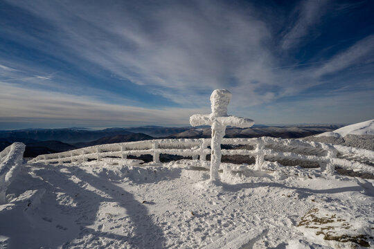 Frozen winter morning on Halicz peak in the Bieszczady Mountains. Snow-covered ridges, icy summit cross and clear sky along the popular Tarnica Halicz Rozsypaniec hiking loop.
