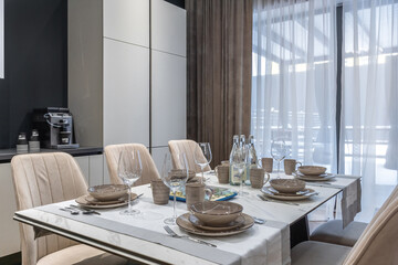 The beautifully set dining table in the modern kitchen is decorated with elegant dishes and wine...
