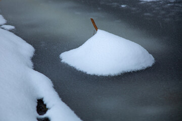 Minimalist winter scene with a small mound of fresh snow resting on frozen water. Strong contrast...