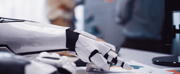 A close-up of a robotic hand interacting with business documents in an office, showcasing automation technology and collaborative work in a modern environment.Noogenesis