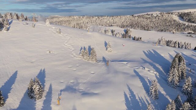 Panorama invernale aereo con neve ripreso da drone sopra Passo Coe sull'Alpe Cimbra di Folgaria nelle Alpi del Trentino-Alto Adige in Italia mentre i cannoni sparano neve