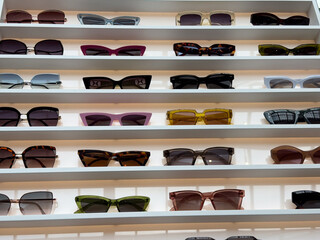 Wall display of colorful sunglasses in modern optical store. Fashion, consumer choice, lifestyle, and visual merchandising through eyewear collection