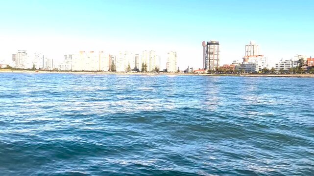 Slow boat movement linking foreground water textures to Punta del Este&rsquo;s skyline.