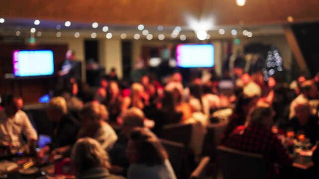 Attendees dressed formally observing performance amidst illuminated screens in upscale setting