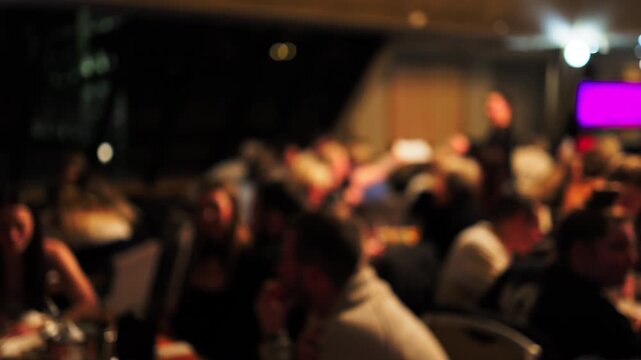 Attendees in formal clothing paying attention to presentation during fundraising celebration