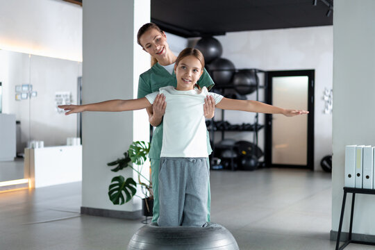 Woman therapist and child performing arm spreading exercising