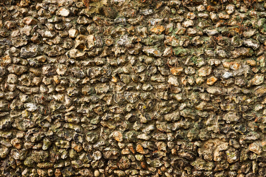 Rough stone wall texture with varied flint rocks and mortar, showing an old rustic construction background pattern
