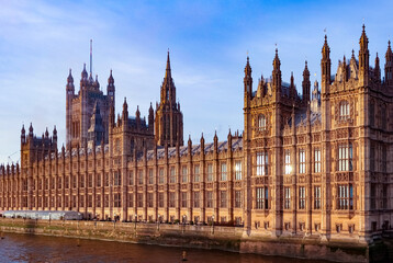 Palace of Westminster and Houses of Parliament along the River Thames, reflecting changing evening...