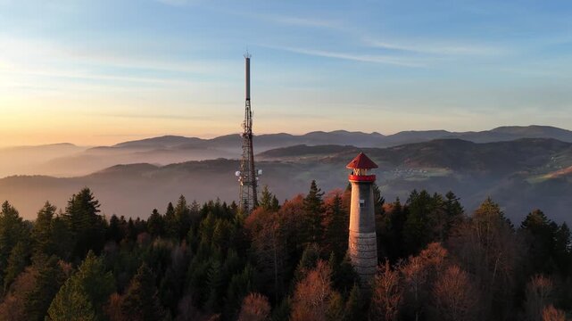 Drohnenaufnahme eines Sendeturms bei Sonnenuntergang mit Aussichtsturm im Vordergrund