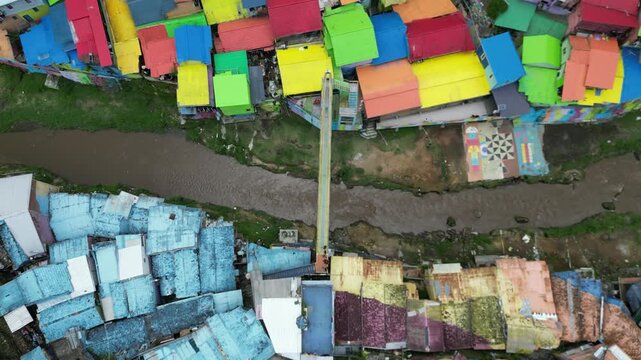 Drone view of Kampoeng Warna Warni Jodipan colorful village in Malang, East Java, Indonesia. Aerial cityscape of vibrant bright houses, Brantas river and bridge. Travel and tourism concept.