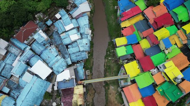 Drone view of Kampoeng Warna Warni Jodipan colorful village in Malang, East Java, Indonesia. Aerial cityscape of vibrant bright houses, Brantas river and bridge. Travel and tourism concept.