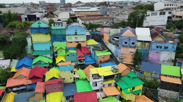 Drone view of Kampoeng Warna Warni Jodipan colorful village in Malang, East Java, Indonesia. Aerial cityscape of vibrant bright houses, Brantas river and bridge. Travel and tourism concept.