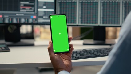 Equity analyst using green screen smartphone to reviews quarterly earnings, assessing stock market value. Trader conducts financial analysis using mockup mobile phone to improve investments