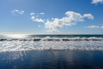 Waves crashing on the tranquil shore under a bright blue sky in Russia