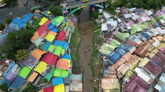 Drone view of Kampoeng Warna Warni Jodipan colorful village in Malang, East Java, Indonesia. Aerial cityscape of vibrant bright houses, Brantas river and bridge. Travel and tourism concept.