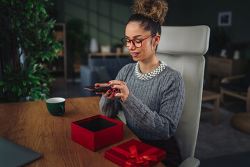 Woman streaming unboxing a red gift box at home
