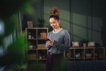 Young woman smiling while using mobile phone at home