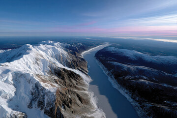 An awe-inspiring aerial perspective of a snow-covered mountain range and river, capturing the beauty of nature's grandeur and tranquility in a magnificent landscape.