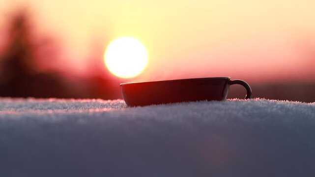 Steaming tea cup resting in fresh snow with soft winter light and calm atmosphere