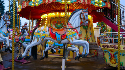 Colorful vintage carousel with decorated horses and bright lights at an amusement park. Classic fairground attraction with festive atmosphere, vivid colors, and nostalgic design. Entertainment concept