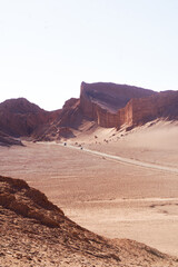 Fototapeta premium Vertical view of a dirt road with tourist vehicles winding through the desert canyon and rock formations of Moon Valley in San Pedro de Atacama.