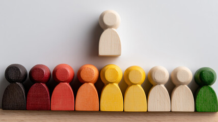 A wooden human figure elevated above a diverse group illustrating leadership selection diversity inclusion and organizational hierarchy concept.
