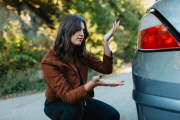 Frustrated young woman looking at scratch on her car