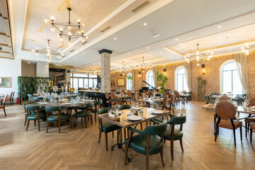 Interior of a spacious empty hotel restaurant with brick walls
