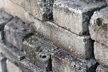 Closeup of grungy grey brick wall. Old used construction bricks in a big stack. Building materials. Monochrome brick all with vintage grunge texture with moss. Abstract texture for background.